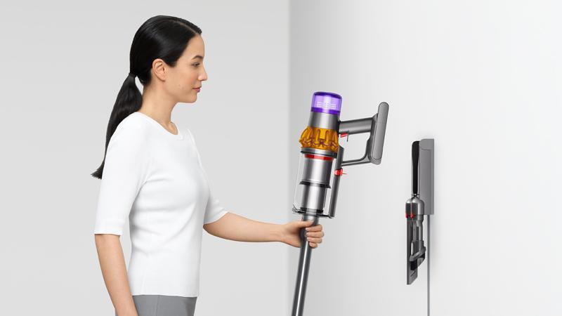 Woman placing the Dyson V15 Detect vacuum on the wall dock
